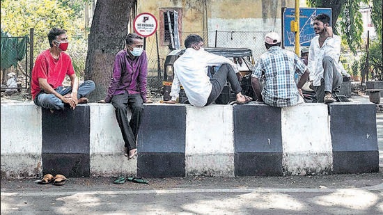 Daily wage workers sit at a pick-up point near Dandekar bridge. (Pratham Gokhale/HT Photo) Daily wage workers sit at a pick-up point near Dandekar bridge. (Pratham Gokhale/HT Photo)