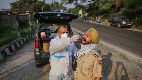 A health worker collects swab samples of a policeman for Covid-19 test in Jammu, (PTI Photo) A health worker collects swab samples of a policeman for Covid-19 test in Jammu, (PTI Photo)