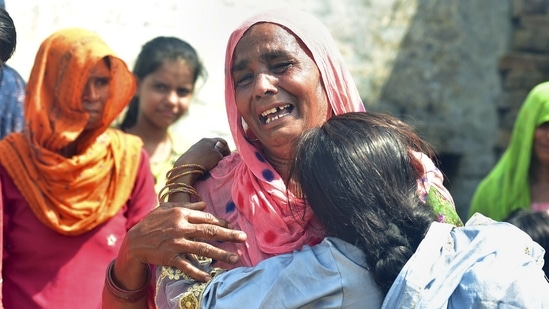 Family members mourn after more people died after allegedly consuming spurious liquor sold by a licensed vendor in Aligarh district.(PTI)