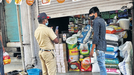 A police official takes action against a shopkeeper for operating after 11 am, near Mandai, Shukrawar peth, on Friday. (HT PHOTO)