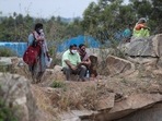Relatives watch from a distance as bodies of people who died of Covid-19 are cremated at an open crematorium on the outskirts of Bengaluru. (AP) Relatives watch from a distance as bodies of people who died of Covid-19 are cremated at an open crematorium on the outskirts of Bengaluru. (AP)