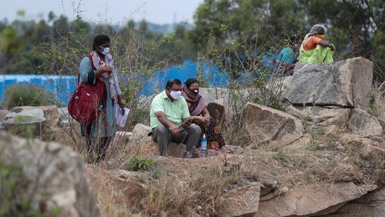 Relatives watch from a distance as bodies of people who died of Covid-19 are cremated at an open crematorium on the outskirts of Bengaluru. (AP) Relatives watch from a distance as bodies of people who died of Covid-19 are cremated at an open crematorium on the outskirts of Bengaluru. (AP)