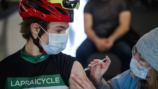 A cyclist receives a dose of the Pfizer-BioNTech Covid-19 vaccine at the Gilles Villeneuve racetrack in Montreal, Quebec, Canada.(Bloomberg)