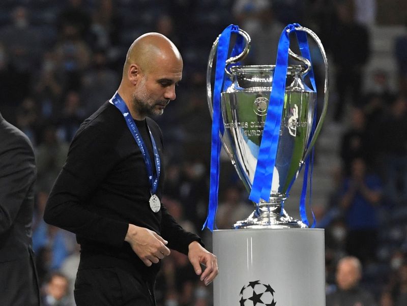 Manchester City manager Pep Guardiola walks past the Champions League trophy after the match.