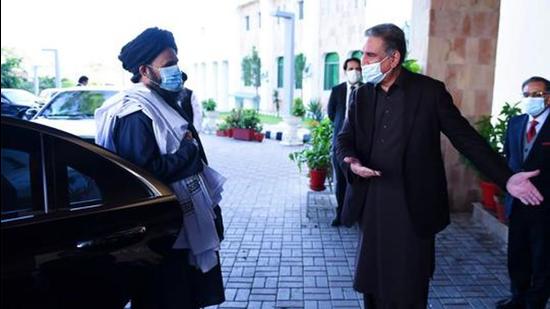 Pakistan's foreign minister Shah Mehmood Qureshi gesturing to Taliban co-founder Mullah Abdul Ghani Baradar (left) upon his arrival with a delegation for talks at the Pakistan Foreign Ministry in Islamabad in December 2020. (AFP)