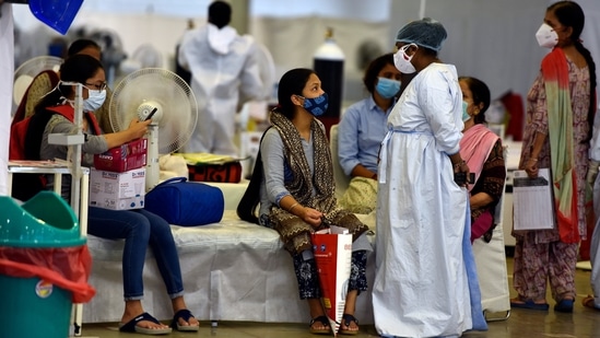 A health worker interacting with people at the Sri Guru Teg Bahadur Covid-19 Care Centre in New Delhi on May 30. The number of people who have recuperated from the disease surged to 2,56,92,342 on May 31 with 2,38,022 patients having recovered in a span of 24 hours, while the case fatality rate stands at 1.17%, health ministry data stated.(Sanjeev Verma / HT Photo)