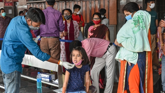 A medical worker collects swab sample of a child passenger for Covid-19 test in Lucknow. It is among the 14 districts where Covid restrictions will continue.(PTI Photo)