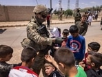 A US Army soldier hands out candy to children while on joint patrol with local allied forces on May 25, 2021 near the Turkish border in northeastern Syria.(AFP) A US Army soldier hands out candy to children while on joint patrol with local allied forces on May 25, 2021 near the Turkish border in northeastern Syria.(AFP)