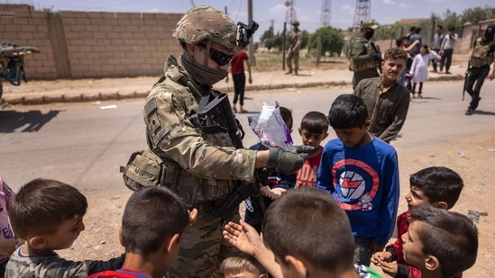 A US Army soldier hands out candy to children while on joint patrol with local allied forces on May 25, 2021 near the Turkish border in northeastern Syria.(AFP) A US Army soldier hands out candy to children while on joint patrol with local allied forces on May 25, 2021 near the Turkish border in northeastern Syria.(AFP)