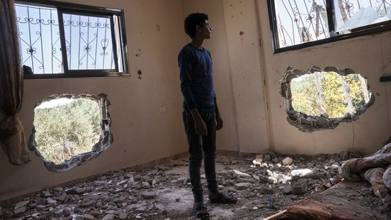 Issat Al-Masri, 18, stands for a portrait in his bedroom that was damaged by shelling prior to the cease-fire, on May 26 in Beit Hanoun, Gaza Strip. Israel blames the destruction on Hamas, which fires imprecise rockets from civilian areas in Gaza in the general direction of civilian areas in Israel. The military says it makes every effort to avoid civilian casualties.(John Minchillo / AP)
