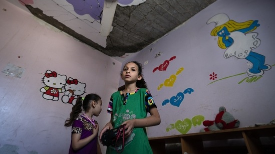 Suroq Al-Masri, 9, and her sister Razan, 4, stand for a portrait in their bedroom that was severely damaged when an airstrike destroyed a neighboring building prior to the cease-fire, on May 26 in Beit Hanoun, Gaza Strip. The two girls survived the early morning airstrike that destroyed a nearby building on May 19, two days before a cease-fire ended the war. But like so many children in Gaza, they will carry the memory of its horrors and devastation.(John Minchillo / AP)