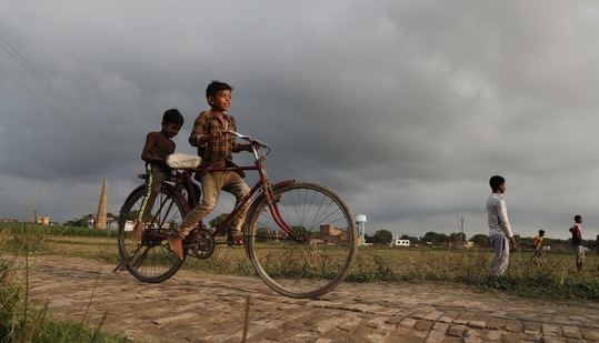 Children ride on a bicycle as they spend time in an agricultural field on the outskirts of Prayagraj(AP Photo) Children ride on a bicycle as they spend time in an agricultural field on the outskirts of Prayagraj(AP Photo)