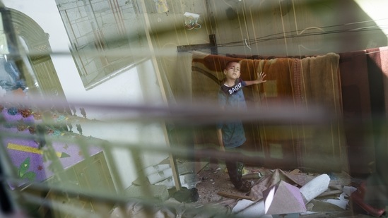 Anas Alhaj Ahmed, 4, stands for a portrait in his bedroom that was damaged by an airstrike prior to the cease-fire, on May 27 in Maghazi, Gaza Strip. The airstrike tore the roof off the bedroom that 4-year-old Anas shared with his sister and left the floor covered in shattered glass. It was the first war in his short life, but most Gazans vividly recall the others.(John Minchillo / AP)
