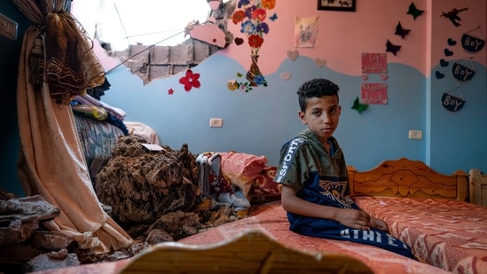 Ibrahim Al-Masri, 10, sits for a portrait in his bedroom that was damaged during an airstrike prior to a cease-fire, on May 26, 2021, in Beit Hanoun, Gaza Strip. So accustomed are residents to the remnants of previous conflicts, that even adolescents can point out homes destroyed in previous rounds of fighting, AP reported.(John Minchillo / AP)