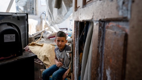Abu Amsha, 6, sits for a portrait in his bedroom that was damaged during an airstrike prior to a cease-fire, on May 26, 2021, in Beit Hanoun, Gaza Strip. Israel says the closure is needed to keep Hamas from re-arming, while the Palestinians and rights groups view it as a form of collective punishment. Either way, it will be a long time before the children whose bedrooms were shattered return to somewhere that feels like home.(John Minchillo / AP)