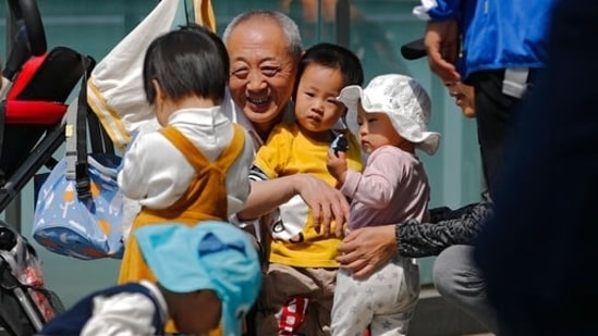 An elderly man plays with children near a commercial office building in Beijing on May 10, 2021. (AP) An elderly man plays with children near a commercial office building in Beijing on May 10, 2021. (AP)