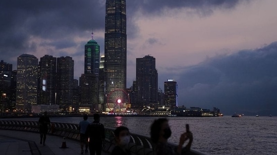 A woman takes pictures in front of high-rise buildings in the Central financial district after sunset in Hong Kong, China March 30, 2021. (Reuters)