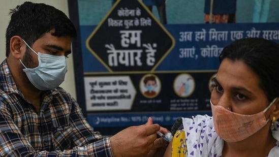 A health worker inoculates a woman with a dose of the Covishield vaccine at a civil hospital in Jind in Haryana