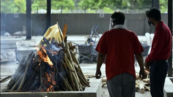 Relatives of a person who died of Covid-19 perform their last rites during a cremation at Sarai Kale Khan crematorium, in New Delhi on May 18. (Sanjeev Verma/HT photo) Relatives of a person who died of Covid-19 perform their last rites during a cremation at Sarai Kale Khan crematorium, in New Delhi on May 18. (Sanjeev Verma/HT photo)