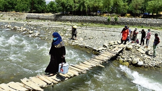 Health workers walk along a wooden bridge during a door-to-door Covid-19 vaccination drive at Tral village in Pulwama, south Kashmir, on Saturday. (Waseem Andrabi/HT photo) Health workers walk along a wooden bridge during a door-to-door Covid-19 vaccination drive at Tral village in Pulwama, south Kashmir, on Saturday. (Waseem Andrabi/HT photo)