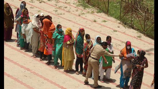 A police woman urging people to maintain social distancing during ration distribution under PM Garib Kalyan Ann Yojana at the Khuda Lohra government school in Chandigarh. (Keshav Singh/HT)