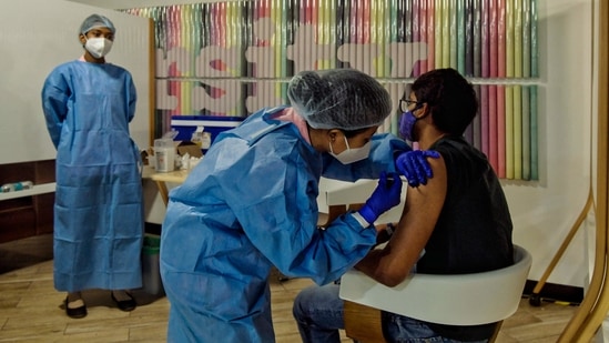 A Health worker inoculates an Amazon employee with a dose of the Covishield vaccine in Bangalore on June 5. The country logged a decrease of more than 6,000 in the number of new infections and a decrease of over 700 in its death toll since June 4 as it continues to recover from the deadly second wave of the pandemic. (Manjunath Kiran / AFP)