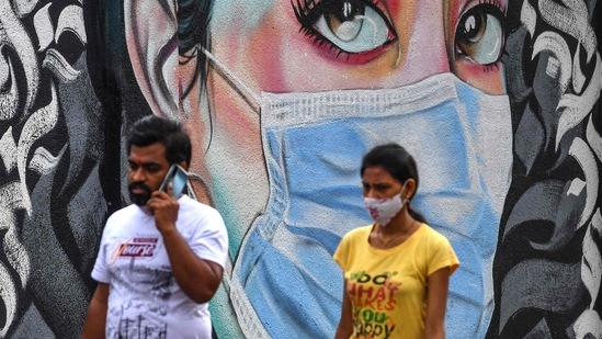 Pedestrians walk past a wall mural representing awareness measures against the Covid-19 coronavirus, in Navi Mumbai on June 6, 2021.(AFP)