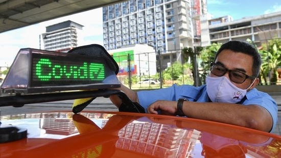 Thai taxi driver Sombat Subin wipes down a sign above his cab showing that he has been vaccinated against the coronavirus disease (COVID-19) in order to attract more customers in Bangkok, Thailand. (REUTERS)