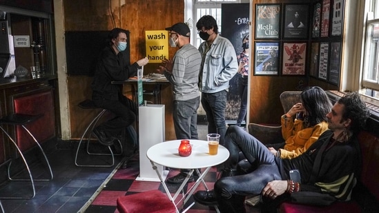 People wearing face masks enter the Moth Club in Hackney, prior to a live show on stage, in London on May 30. Working artists started playing again across London on May 17, but to small, socially distanced crowds.(Alberto Pezzali / AP)