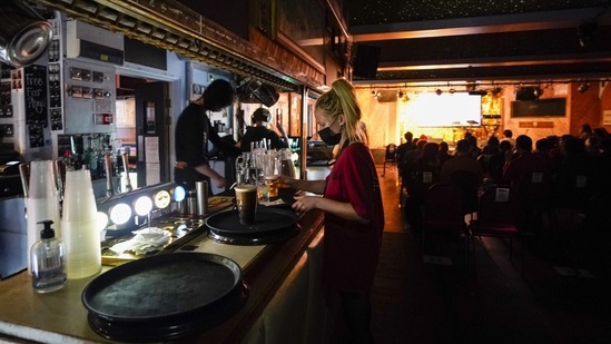 A waitress collects drinks whilst wearing a face mask at the Moth Club in Hackney, prior to a live show on stage, in London on May 30. Milwaukee, a 31-year-old Italian multi-instrumentalist whose real name is Iacopo Bertelli, put out his third album in late January 2020, less than two months before Britain's first coronavirus lockdown.(Alberto Pezzali / AP)