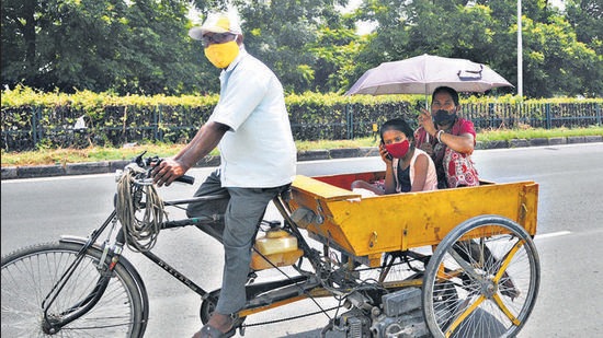 A family using an umbrella and cap to shield themselves from the scorching sun in Chandigarh on Monday. (Ravi Kumar/HT)