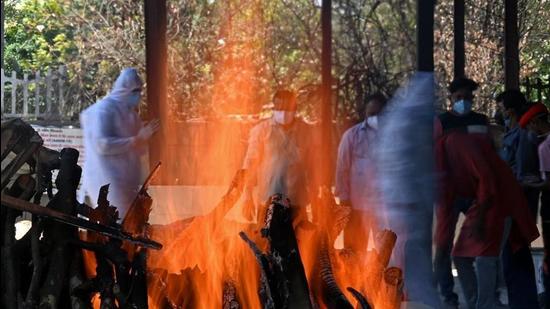 Family and relatives stand next to a funeral pyre of a Covid-19 victim at a crematorium in New Delhi on May 24. (File photo) Family and relatives stand next to a funeral pyre of a Covid-19 victim at a crematorium in New Delhi on May 24. (File photo)