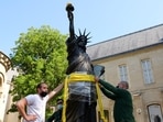 Workers put strap around a 2.83 meter original replica of the Statue of Liberty before being lifted by a crane from outside the Musee des Arts et Metiers in Paris before it departs for Ellis Island in New York to arrive on Independence Day, France, June 7, 2021. REUTERS/Noemie Olive