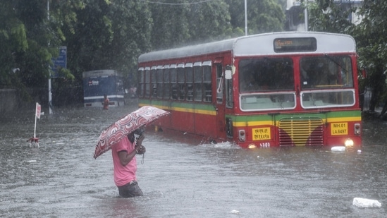 A man makes his way across a flooded street during heavy rains in Mumbai, on June 9. The southwest monsoon arrived in Mumbai on June 9 morning, with most parts of the city receiving intense showers as early as 4am, HT reported.(Rafiq Maqbool / AP)