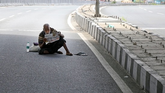 A homeless person reading a newspaper in the middle of the road during a lockdown imposed amid the rise in Covid-19 cases in Bengaluru. (ANI Photo) A homeless person reading a newspaper in the middle of the road during a lockdown imposed amid the rise in Covid-19 cases in Bengaluru. (ANI Photo)