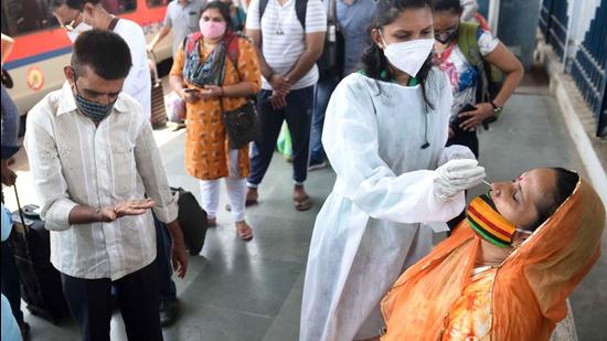 A BMC healthcare worker collects swab samples for Covid-19 test of passengers arriving at Dadar station in Mumbai on June 4. (Satish Bate/HT photo)