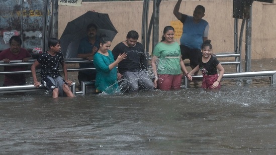 Children play near a flooded bus stop during heavy rains in Mumbai, on June 9. According to Brihanmumbai Municipal Corporation (BMC) officials, in the last 24 hours, eastern suburbs received the maximum rainfall of 65mm followed by western suburbs and island city getting 48mm of rainfall, HT reported.(Rafiq Maqbool / AP)