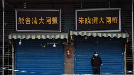 In this file photo taken on January 24, 2020, a security guard stands outside the Huanan Seafood Wholesale Market where the coronavirus was detected in Wuhan, China. (AFP)