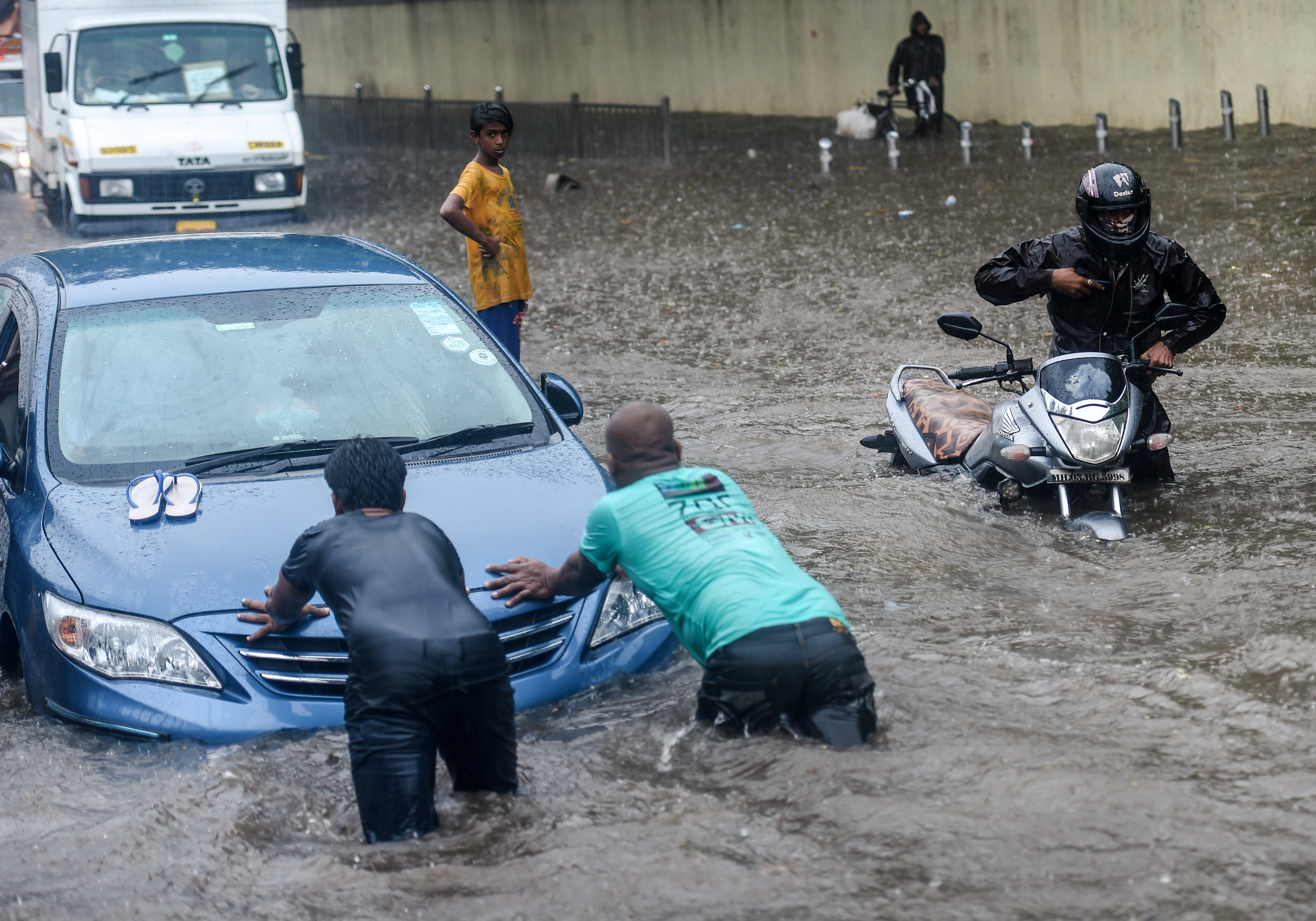 Two men try to push the vehicle as it stopped working due to a waterlogged road during heavy rain, at Kings Circle, in Mumbai, Wednesday, June 9, 2021. (PTI) Two men try to push the vehicle as it stopped working due to a waterlogged road during heavy rain, at Kings Circle, in Mumbai, Wednesday, June 9, 2021. (PTI)