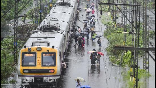 Stranded local train commuters walk on the waterlogged railway tracks during rain, at Kurla in Mumbai on Wednesday, June 9. (PTI) Stranded local train commuters walk on the waterlogged railway tracks during rain, at Kurla in Mumbai on Wednesday, June 9. (PTI)