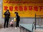 A family stands at the entrance to an underground retail street in Aksu in western China's Xinjiang Uyghur Autonomous Region.