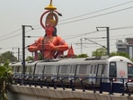 A Delhi Metro train runs on its tracks in the backdrop of a Hanuman temple (representational image). A Delhi Metro train runs on its tracks in the backdrop of a Hanuman temple (representational image).