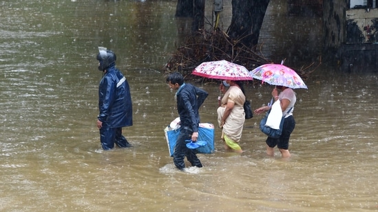 People wade through a waterlogged street during heavy rains on the first day of the monsoon at Hindmata in Mumbai on June 9. The onset came with two days of continuous showers, with residents only finding some respite on June 11 morning when the rains took a break in the city and its suburbs, PTI reported.(Bhushan Koyande / HT Photo)