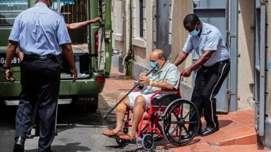 Antigua and Barbuda businessman Mehul Choksi is taken to a police van via a wheelchair by a police officer after attending a court hearing, in Roseau, Dominica.(AP)