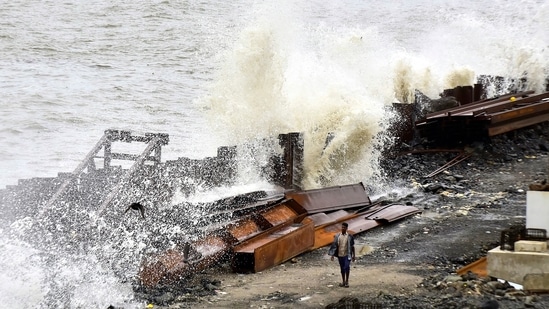 A worker on the Coastal Road project looks towards waves crashing on the shore during high tide at Marine Drive in Mumbai on June 10. The civic administration had been on its toes as a high tide of 4.34 metres was expected at around 12.54 pm on June 11. But as the rain has stopped in the morning, they have heaved a sigh of relief, PTI reported.(Anshuman Poyrekar / HT Photo)
