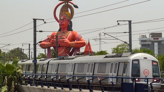 A Delhi Metro train runs on its tracks in the backdrop of a Hanuman temple (representational image).(PTI)