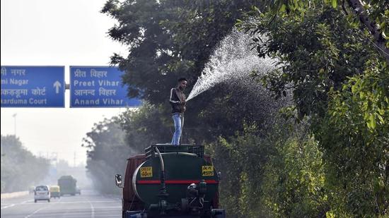 A PWD worker sprays water on trees as a pollution control measure. (HT Archive)