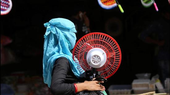 A woman carries a table fan on a hot summer day in Jammu on Friday. (PTI) A woman carries a table fan on a hot summer day in Jammu on Friday. (PTI)