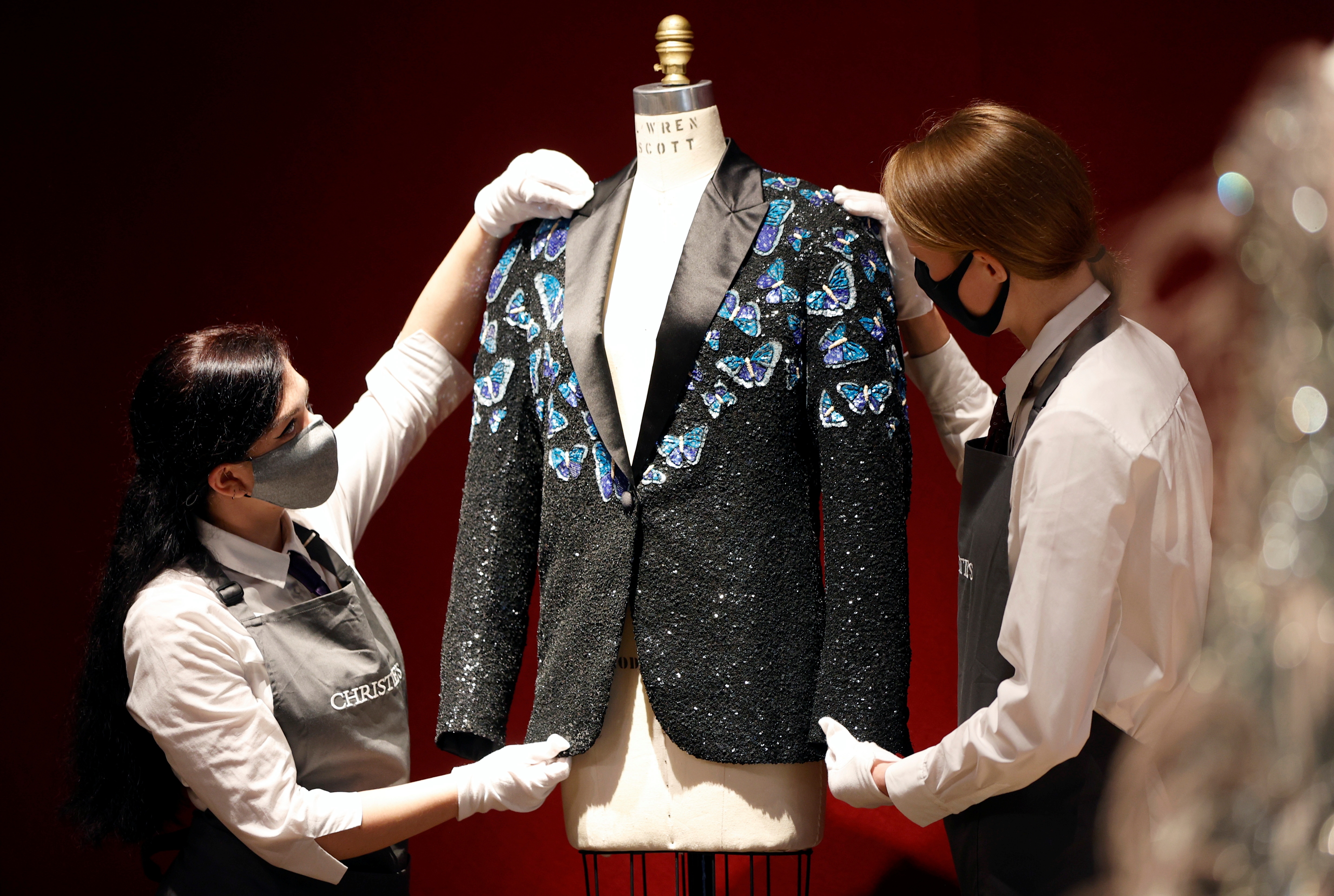 Gallery assistants pose for a photograph with the Butterfly jacket designed for Mick Jagger by designer L’Wren Scott at Christie’s in London, Britain, June 10, 2021. (REUTERS)