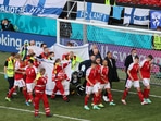  Denmark's Christian Eriksen is stretchered off the pitch after collapsing during the match as his teammates react.